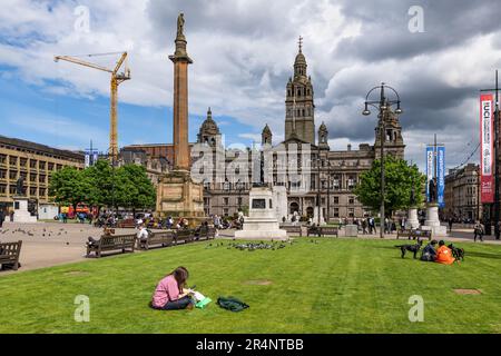 George Square im Stadtzentrum von Glasgow in Schottland, Großbritannien. Glasgow City Chambers, Scott Monument und Leute Sightseeing und Entspannen Stockfoto