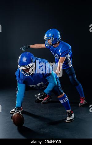 Zwei American Football-Spieler sind bereit, das Spiel auf schwarzem Hintergrund zu beginnen. Stockfoto