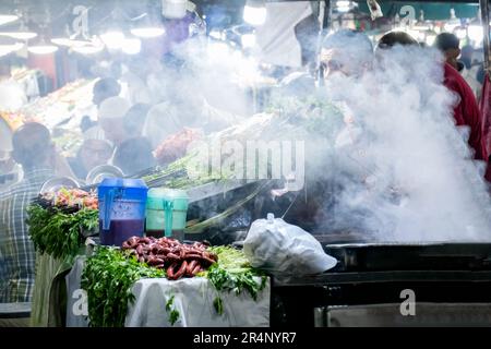 Köche bereiten marokkanisches Street Food in einem Nachtmarkt im Freien auf dem Platz Jemaa el Fna, Marrakesch, zu. Stockfoto