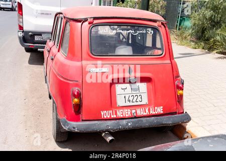 Ein alter roter Renault 4-Wagen, der auf einer Straße in Marrakesch, Marokko, geparkt hat. Auf dem Kofferraum steht der Slogan „You'll Never Walk Alone“ Stockfoto