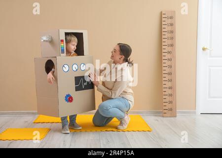 Ein kleiner Junge im Roboterkostüm mit Kindermädchen zu Hause Stockfoto