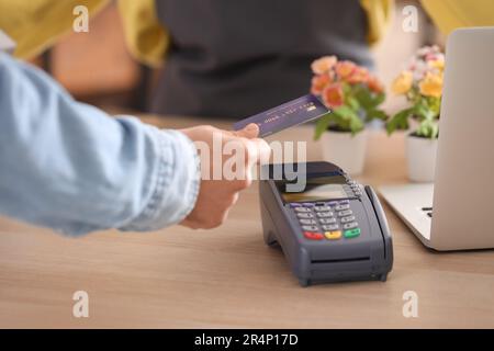 Junger Mann, der mit Kreditkarte über den Zahlungsterminal im Blumenladen bezahlt Stockfoto