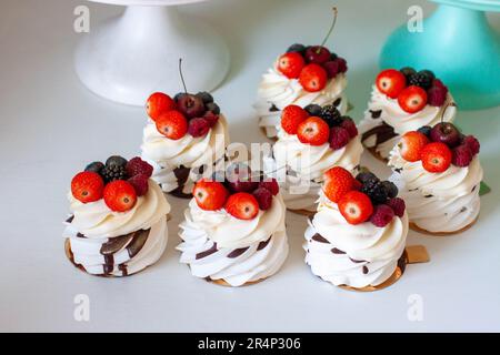Köstliche Mini-Pavlova-Baiser-Kuchen mit frischen Himbeeren, Erdbeeren und Blaubeeren auf weißem Hintergrund Stockfoto