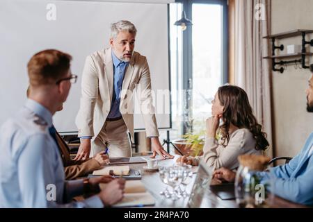Reifer Geschäftsmann, der eine Präsentation in einem Geschäftstreffen hält. Stockfoto