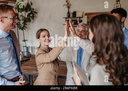 Ein glückliches Business-Team, das eine High Fives-Geste gibt, während es lacht und seinen Erfolg feiert Stockfoto