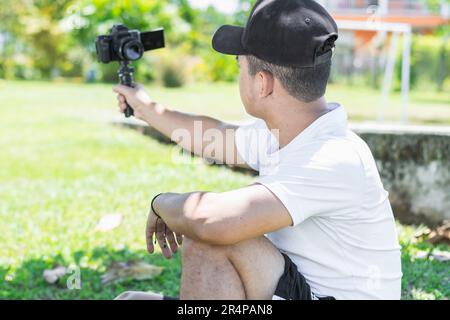 Blick auf die Rückseite eines jungen lateinamerikanischen Bloggers, der sich selbst mit einer Handkamera aufnimmt. Stockfoto