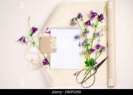Aquilegia-Blumen, Notizbuch, leere Modelle, Draufsicht, Kopierraum. Sommermockup-Szene. Stockfoto