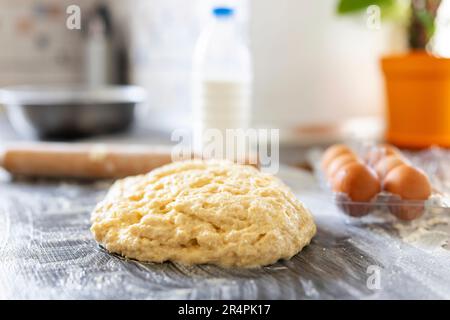 Hausgemachter Teig, Walznadel und Backzutaten auf einem Holztisch in der Küche Stockfoto