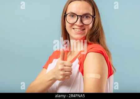 Geimpfte Frau mit Brille macht Gesten mit Daumen nach oben Stockfoto