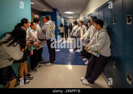 Uniformierte multirassische Schüler in einem katholischen Highschool-Gespräch in Südkalifornien im Flur zwischen den Kursen. Stockfoto