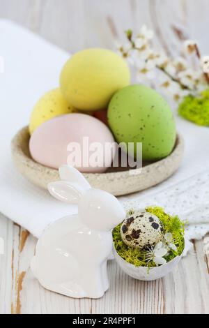 Ostertischdeko mit bunten Eiern und Keramik rabit Figur. Festliche Einrichtung Stockfoto