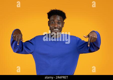 Attraktiver junger afroamerikanischer Mann, der nach unten zeigt Stockfoto