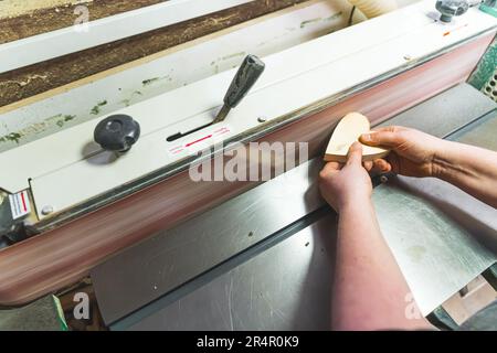 Schreiner glätten eines herzförmigen Holzstücks mit einer Schleifmaschine in einer Werkstatt. Hochwertiges Foto Stockfoto