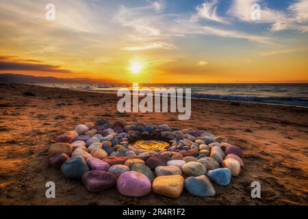 Während des Sonnenuntergangs am Strand werden heilige Ritualsteine für spirituelle Zeremonien in Einem Kreis angeordnet Stockfoto