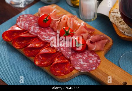 Spanische leckere Mahlzeit Würste und Jamon mit Tomaten schneiden, Nahaufnahme Stockfoto