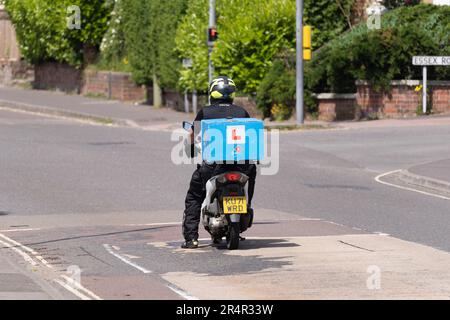 Ein Mopedfahrer mit L-Teller, der Pizza für Dominos Pizza, Basingstoke, Großbritannien, liefert. Konzept: Fastfood-Lieferung, Wirtschaftlichkeit, Auszubildender Mitarbeiter Stockfoto