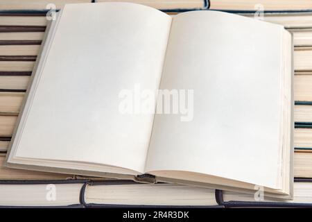 Ein offenes Tagebuch mit leeren Seiten liegt vor dem Hintergrund schäbiger Bücher, die verkehrt herum liegen Stockfoto