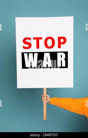 Eine Frau mit einem Poster mit den Worten "Stop war" auf hellblauem Hintergrund, Nahaufnahme Stockfoto