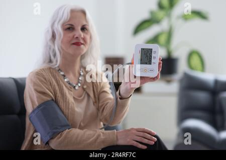 Ältere Frau misst den Blutdruck mit einem digitalen Tonometer Stockfoto