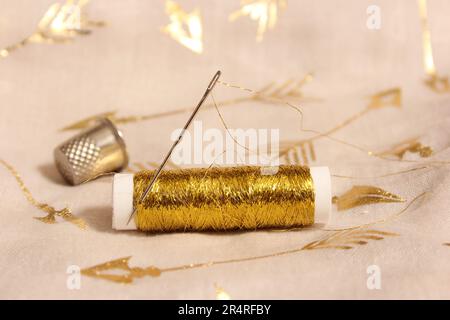 Rolle mit Goldfaden und Kaugummi auf metallischem Chiffon-Stoff Stockfoto