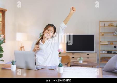 Entspannendes Zeitkonzept, Frau trinkt Kaffee und Arme strecken, nachdem sie müde von der Arbeit im Home Office war. Stockfoto