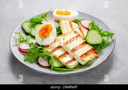 Gesundes Ketogenic Paleo Gericht, gegrilltes Halloumi mit Salat, Rettich, Gurke, und gekochtes Ei auf hellem Hintergrund, Detox, Diet Lunch Stockfoto