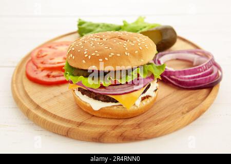 Burger Steak Cutlets mit Gewürzen, Käse, Tomaten, Salat und Brötchen auf weißem Hintergrund. Draufsicht Stockfoto