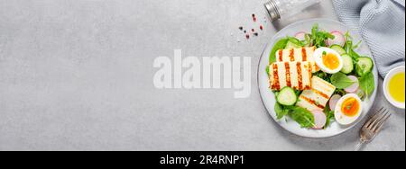 Gesundes Ketogenic Paleo Gericht, gegrilltes Halloumi mit Salat, Rettich, Gurke, und gekochtes Ei auf hellem Hintergrund, Detox, Diet Lunch Stockfoto