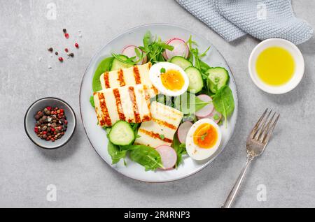 Gesundes Ketogenic Paleo Gericht, gegrilltes Halloumi mit Salat, Rettich, Gurke, und gekochtes Ei auf hellem Hintergrund, Detox, Diet Lunch Stockfoto