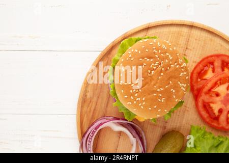 Burger Steak Cutlets mit Gewürzen, Käse, Tomaten, Salat und Brötchen auf weißem Hintergrund. Draufsicht Stockfoto