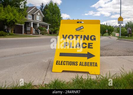 Calgary, Alberta, Kanada. Mai 29. 2023. Vorderansicht eines Hinweisschilds für die Wahlen zum Wahlort Alberta, gelber doppelseitiger Bodenständer. Stockfoto