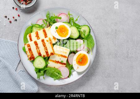 Gesundes Ketogenic Paleo Gericht, gegrilltes Halloumi mit Salat, Rettich, Gurke, und gekochtes Ei auf hellem Hintergrund, Detox, Diet Lunch Stockfoto