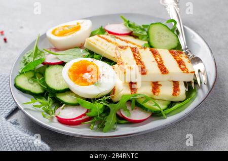 Gesundes Ketogenic Paleo Gericht, gegrilltes Halloumi mit Salat, Rettich, Gurke, und gekochtes Ei auf hellem Hintergrund, Detox, Diet Lunch Stockfoto