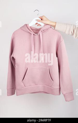 Frau mit leerem rosa Hoodie in der Hand, Modell für dein eigenes Design. Draufsicht Stockfoto