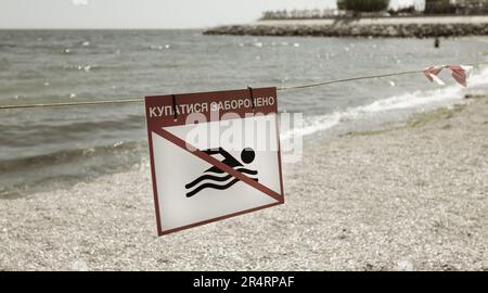 Leuchtend rotes Schild „No Swimming“ am Sandstrand der Stadt in Odessa während Russlands Angriff auf die Ukraine. Schwimmen ist verboten! Sie nähern sich dem Wasser Stockfoto