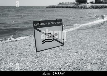 Leuchtend rotes Schild „No Swimming“ am Sandstrand der Stadt in Odessa während Russlands Angriff auf die Ukraine. Schwimmen ist verboten! Sie nähern sich dem Wasser Stockfoto