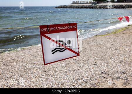 Leuchtend rotes Schild „No Swimming“ am Sandstrand der Stadt in Odessa während Russlands Angriff auf die Ukraine. Schwimmen ist verboten! Sie nähern sich dem Wasser Stockfoto