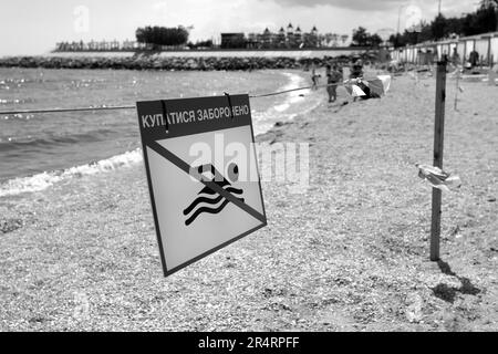 Leuchtend rotes Schild „No Swimming“ am Sandstrand der Stadt in Odessa während Russlands Angriff auf die Ukraine. Schwimmen ist verboten! Sie nähern sich dem Wasser Stockfoto