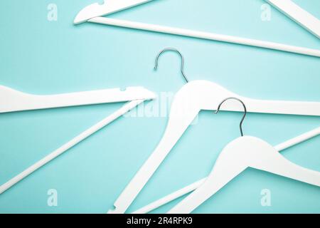 Viele weiße Holzbügel auf blauem Hintergrund. Ladenkonzept, leerer Kleiderbügel. Stockfoto