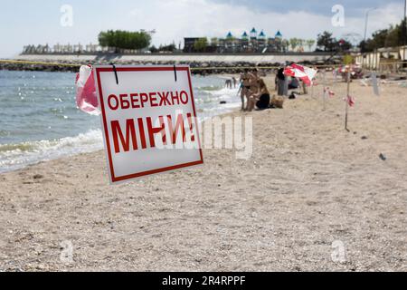 ODESSA, UKRAINE - 15. MAI 2023: Minengefahrenschild am Sandstrand des städtischen Meeres in Odessa während des russischen Angriffs auf die Ukraine. Schwimmen ist verboten! Ca Stockfoto