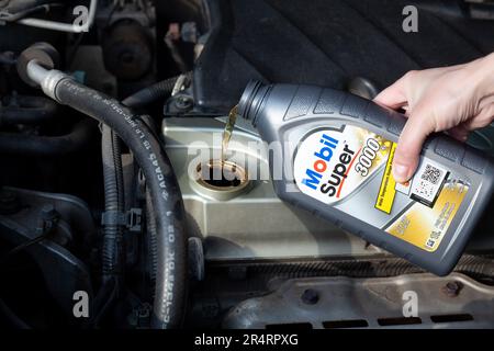 Öl in den Automotor gießen, Nahaufnahme. Synthetisches Mobil-Superöl für Motor. Ukraine, Charkiv - 29. Mai 2023 Stockfoto