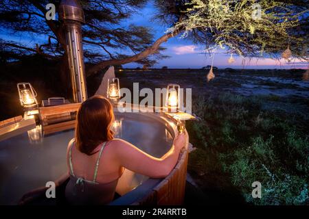 Eine Frau genießt den holzbefeuerten Wannen-Whirlpool in der Honeymoon Suite - Onguma The Fort, Onguma Game Reserve, Namibia, Afrika Stockfoto