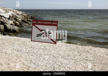 Leuchtend rotes Schild „No Swimming“ am Sandstrand der Stadt in Odessa während Russlands Angriff auf die Ukraine. Schwimmen ist verboten! Sie nähern sich dem Wasser Stockfoto