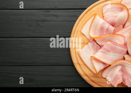 Frischer, kaltgeschnittener Speck auf dem Holzschneidbrett auf dunklem Hintergrund. Draufsicht. Stockfoto