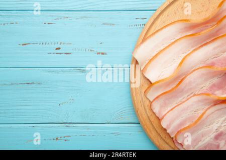 Frischer, roher Speck auf dem Holzschneidbrett in blauer Farbe. Draufsicht. Stockfoto