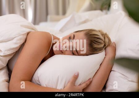 Weiße junge Frau in Übergröße mit Kissen, die zu Hause auf einem gemütlichen Bett schläft, Kopierbereich Stockfoto