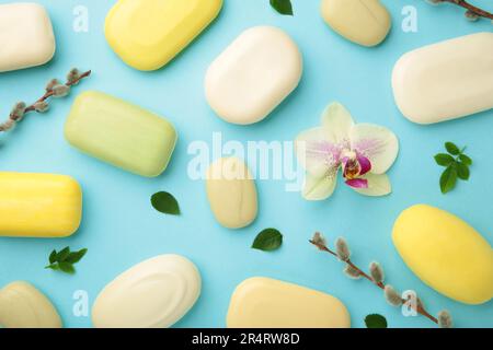 Verschiedene gelbe und weiße Seifen mit Blumen. Viel feste Seife für Hygiene und Sauberkeit auf blauem Hintergrund. Draufsicht. Stockfoto