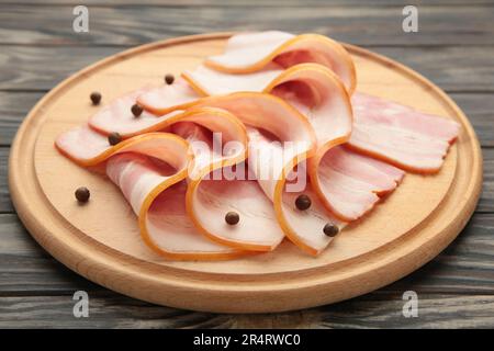 Frischer, roher Speck auf dem Holzschneidbrett auf braunem Hintergrund. Draufsicht. Stockfoto