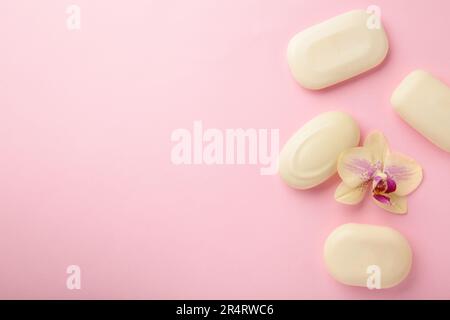 Verschiedene weiße Seifen mit Blumen. Viel feste Seife für Hygiene und Sauberkeit auf pinkfarbenem Hintergrund. Draufsicht. Stockfoto