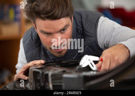 Junger, gutaussehender Kutscher bei der Arbeit in der Garage Stockfoto